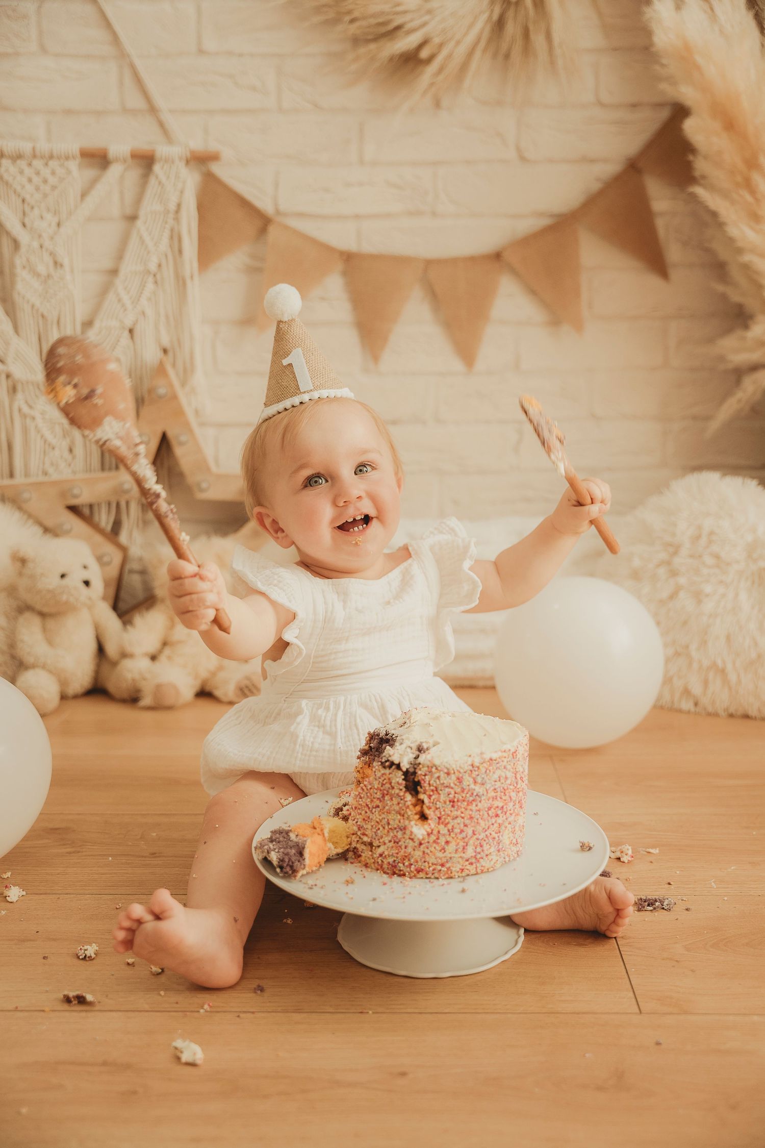 A cake smash photo series showing a first birthday celebration with white and pink decorations and a progressively destroyed cake.