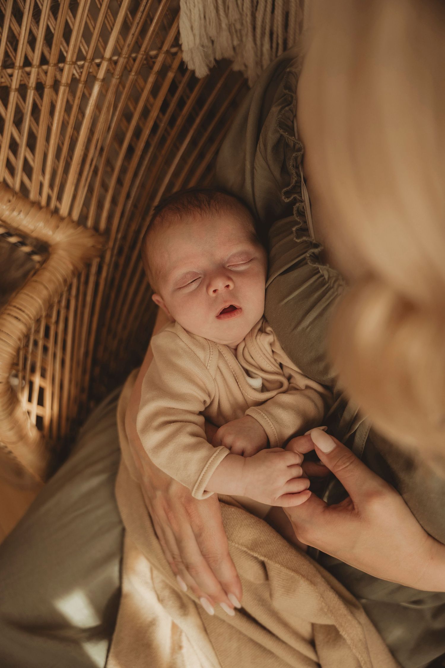 Series of serene newborn baby photos showing gentle hands cradling an infant against soft brown wicker backdrop.