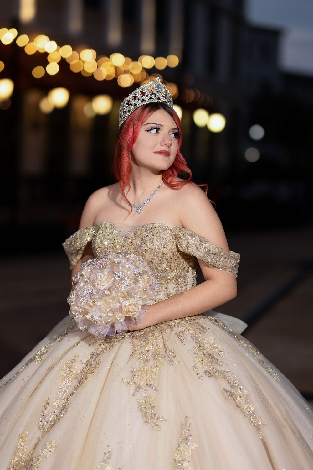 An elegant cream-colored ballgown with intricate gold details photographed outdoors at dusk.