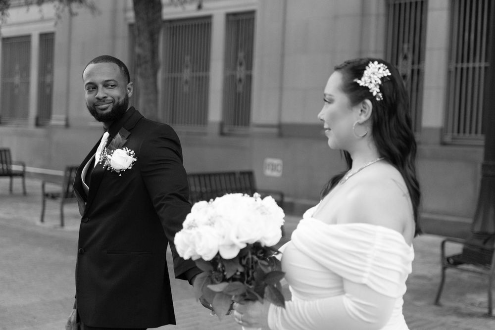 A series of black and white wedding photos showing the bride and groom in various romantic poses outside a building.