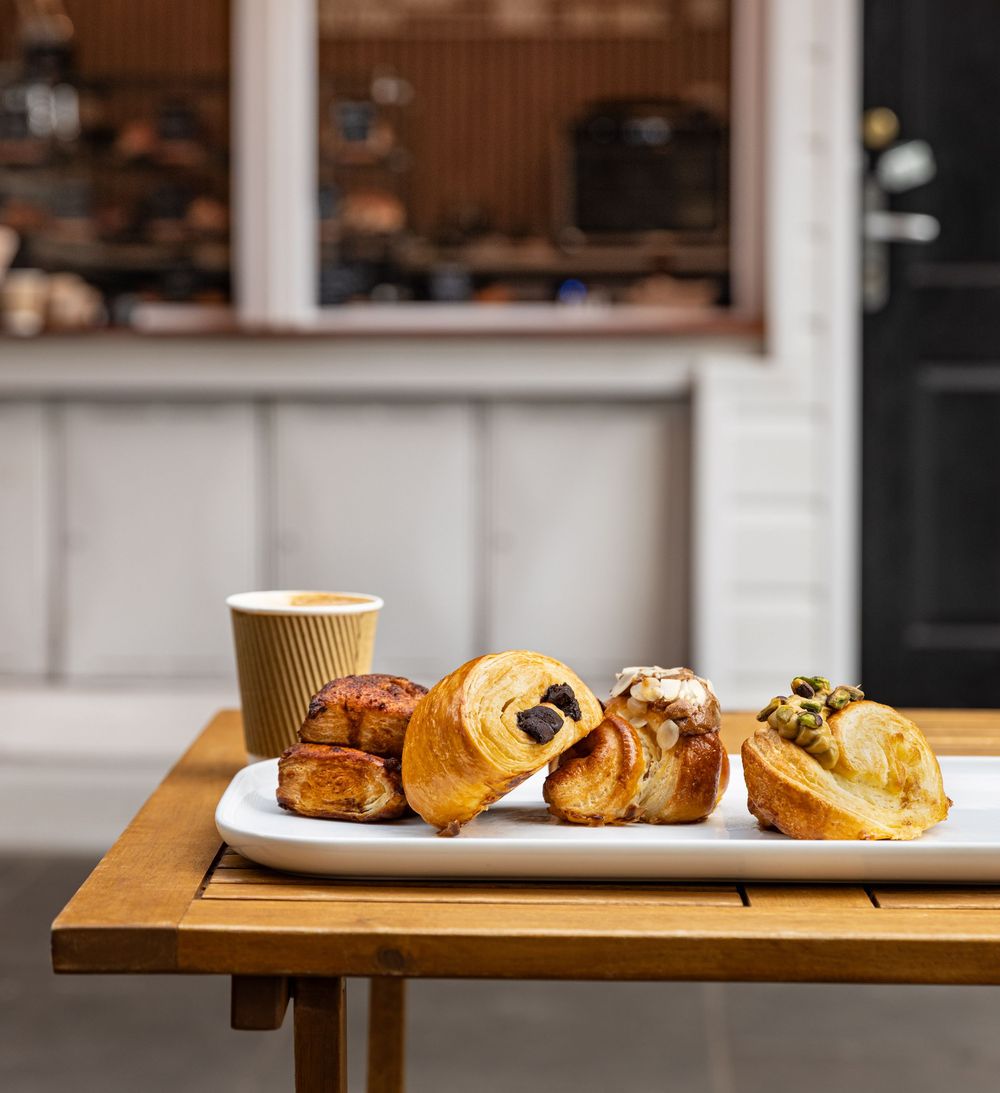 Plate of freshly made croissants served on a patio table in front of cafe captured by Los Angeles food and lifestyle photographer.