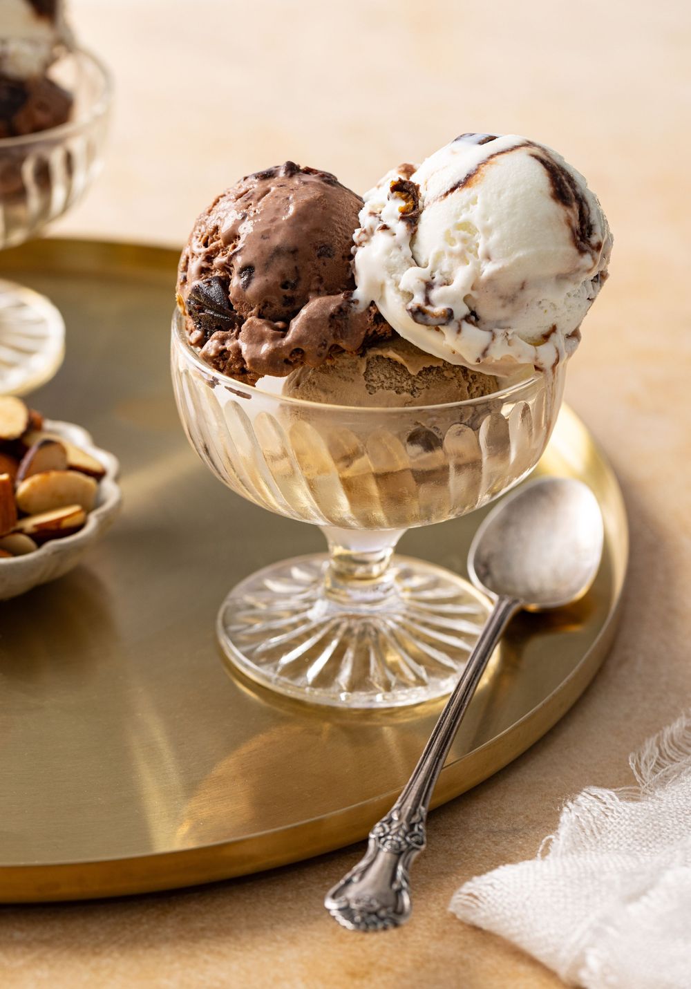 Dessert glass filled with scoops of ice cream served with a bowl of almonds on the side captured by Los Angeles food photographer.