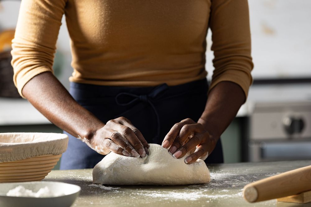 Food lifestyle photograph of a woman kneading bread dough captured in Los Angeles photography studio.