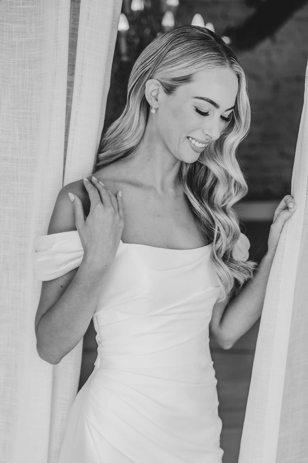 Black and white photo series showing a woman in white dress with wavy blonde hair posing elegantly against a wall.