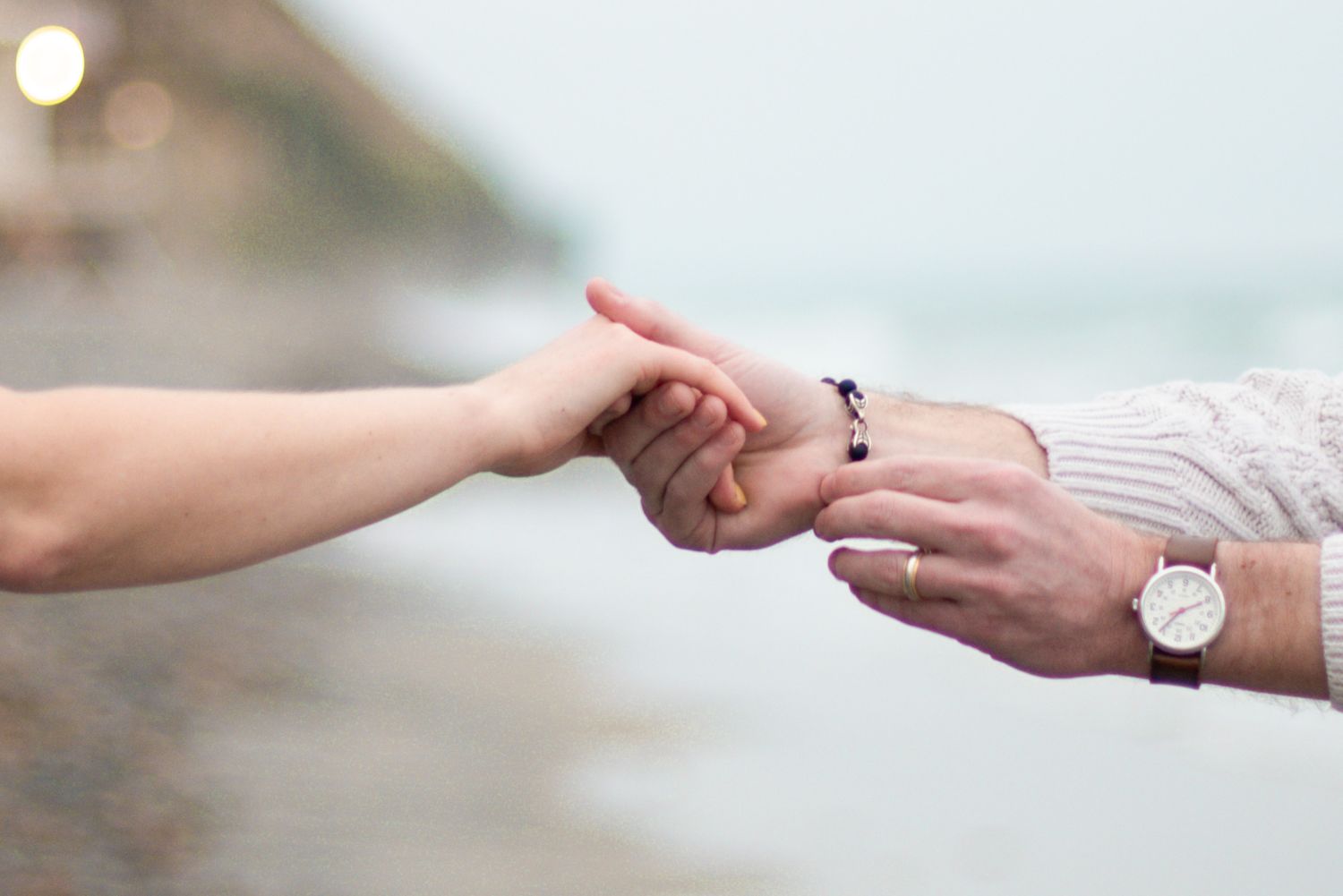 A sequence of hands gently holding and reaching for each other against a light background shows connection and tenderness.