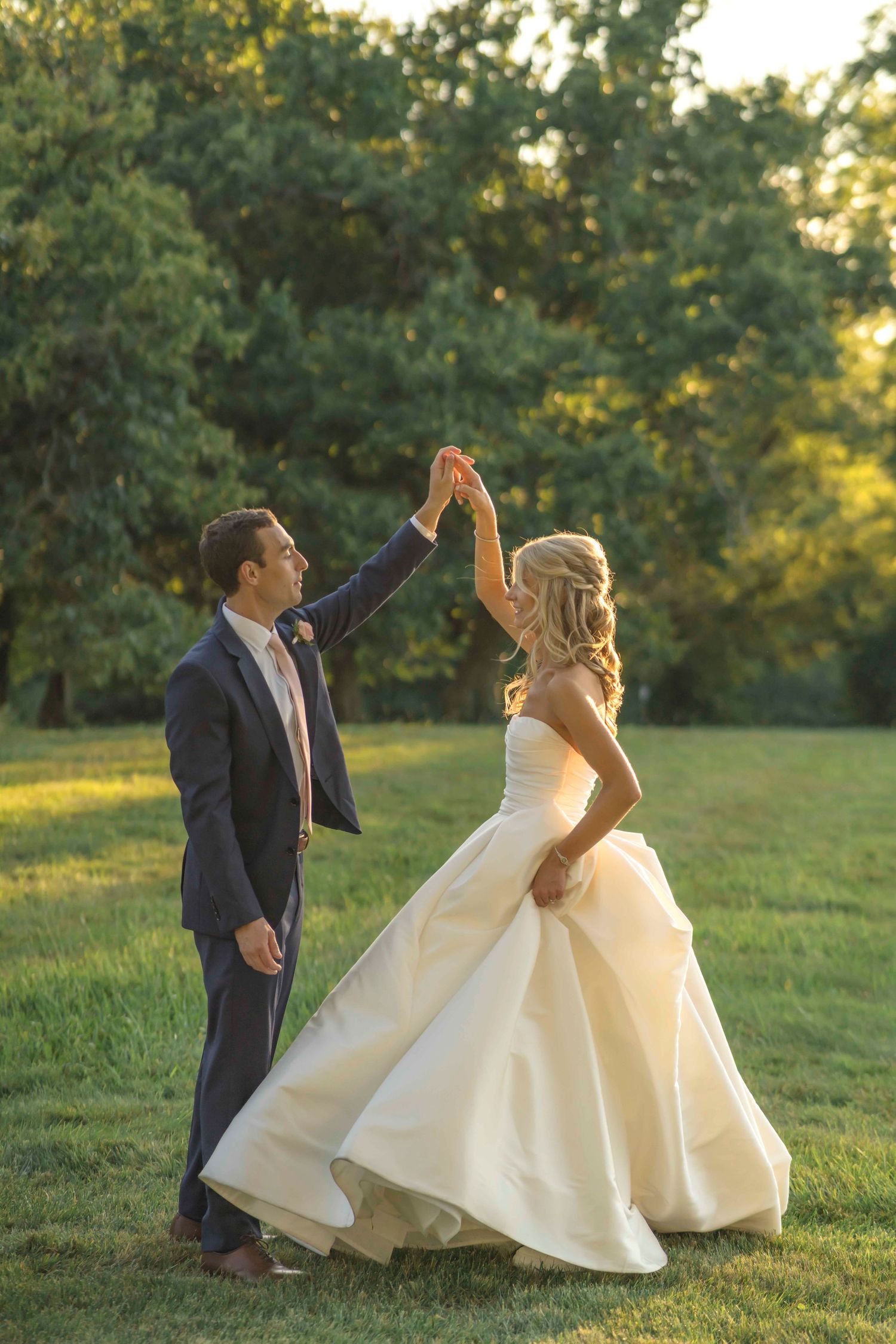 A joyful dancing moment between newlyweds in a sunlit garden setting. Cincinnati wedding Pinecroft Estates & Delightmore.