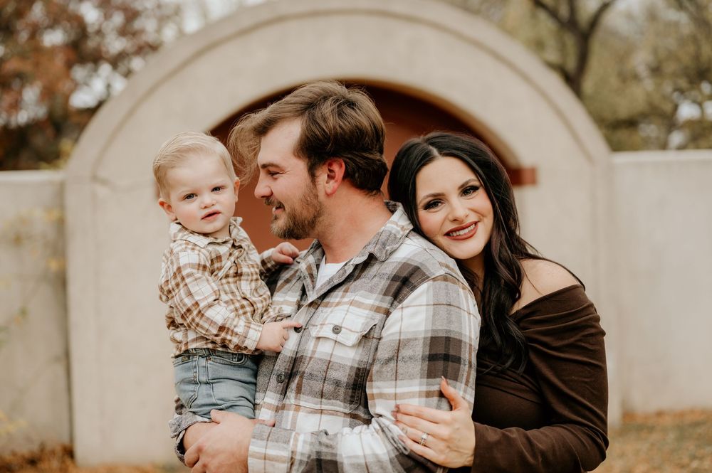 Outdoor family portrait session with warm autumn tones and stone archway.