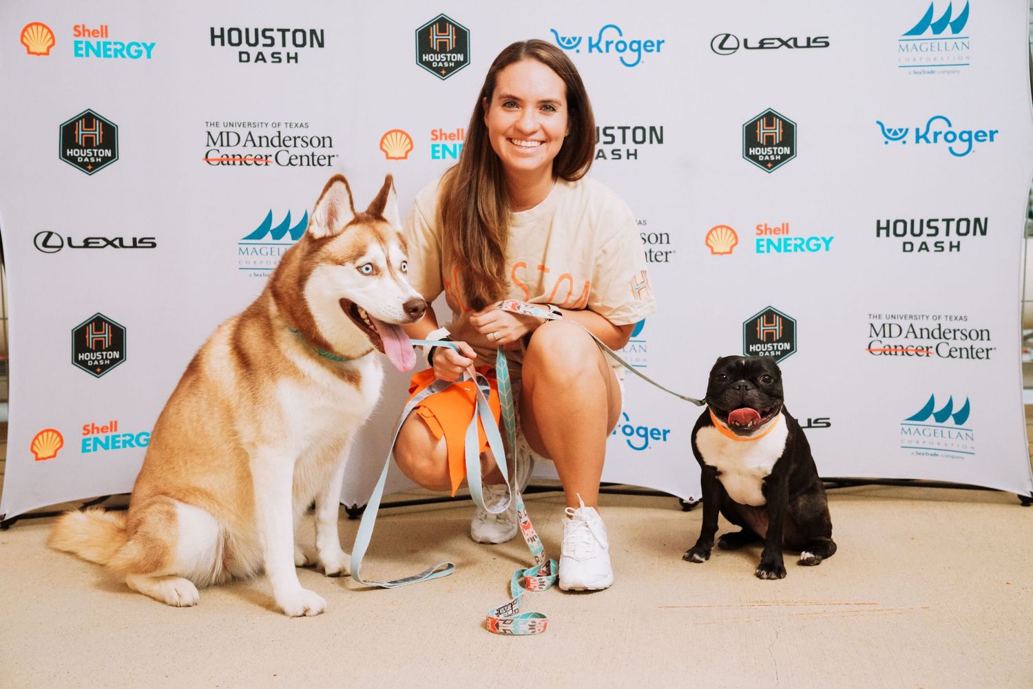 Event backdrop with sponsor logos including Shell, Houston, and Lexus with pets in the foreground.