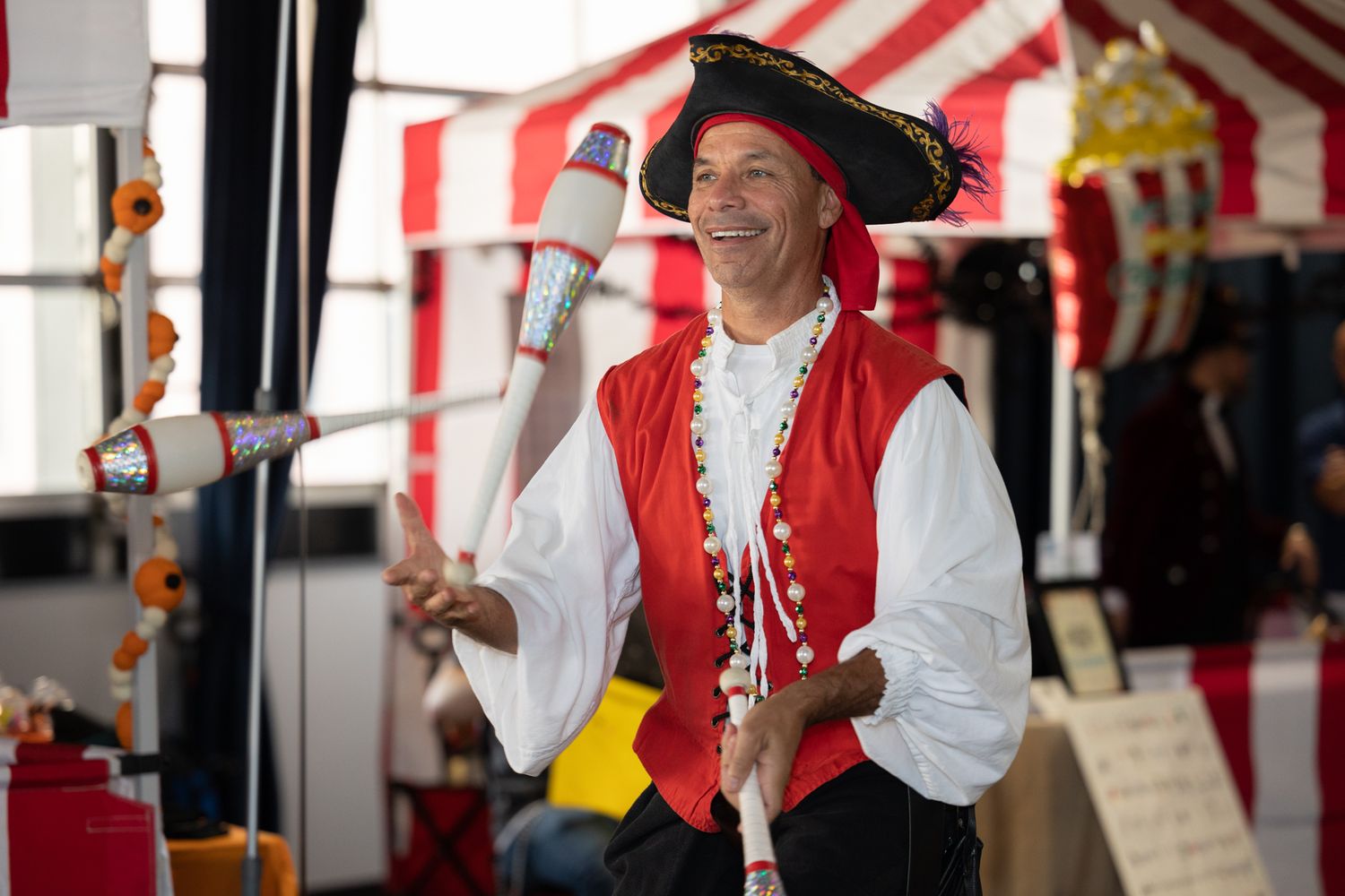 Performers in pirate costumes entertaining at a carnival-themed event with striped decorations.