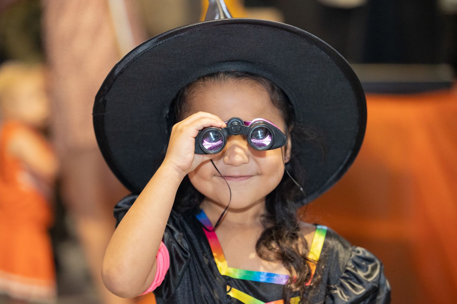 Children wearing large black witch hats at a Halloween or costume party event.