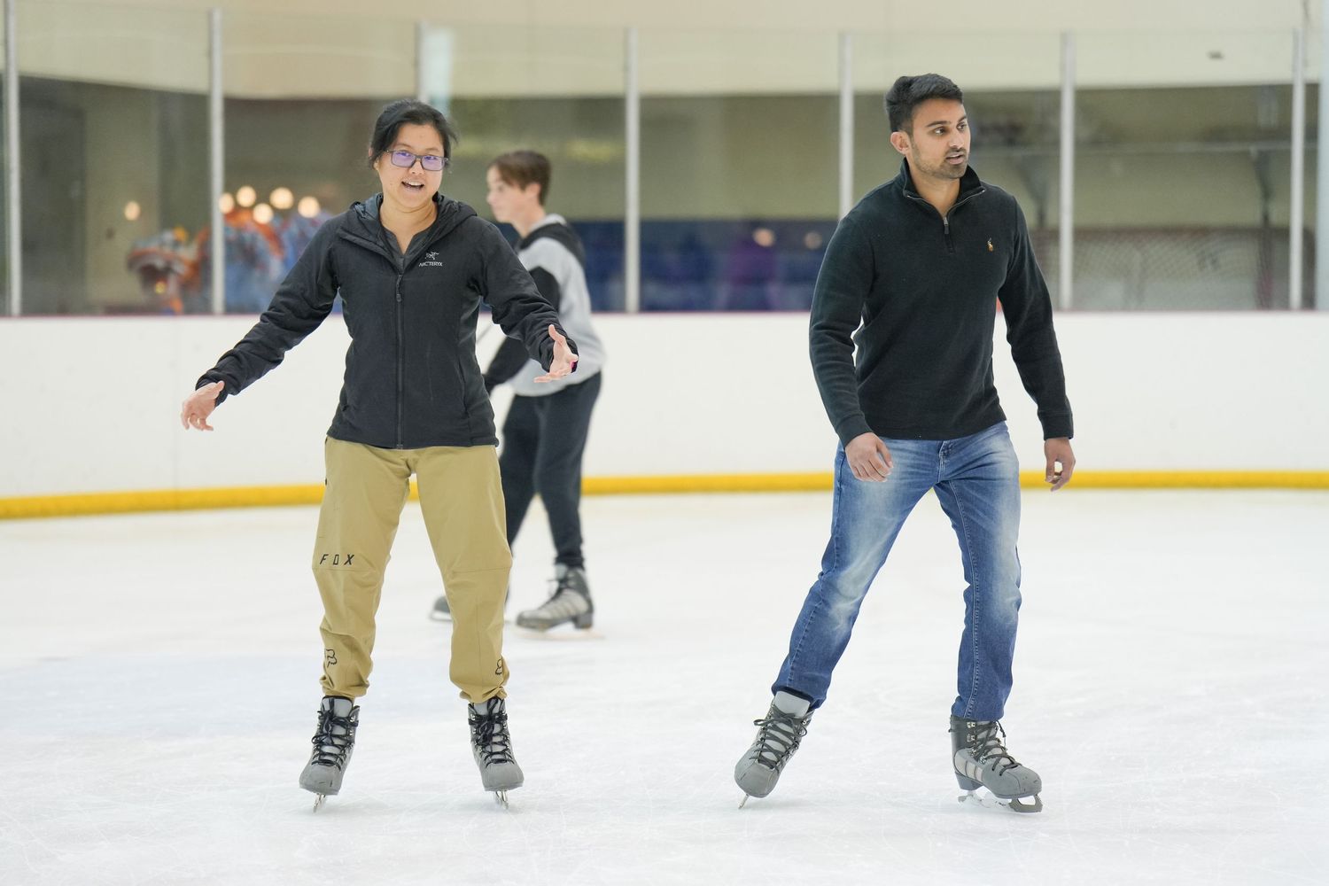 People ice skating together at an indoor ice rink.