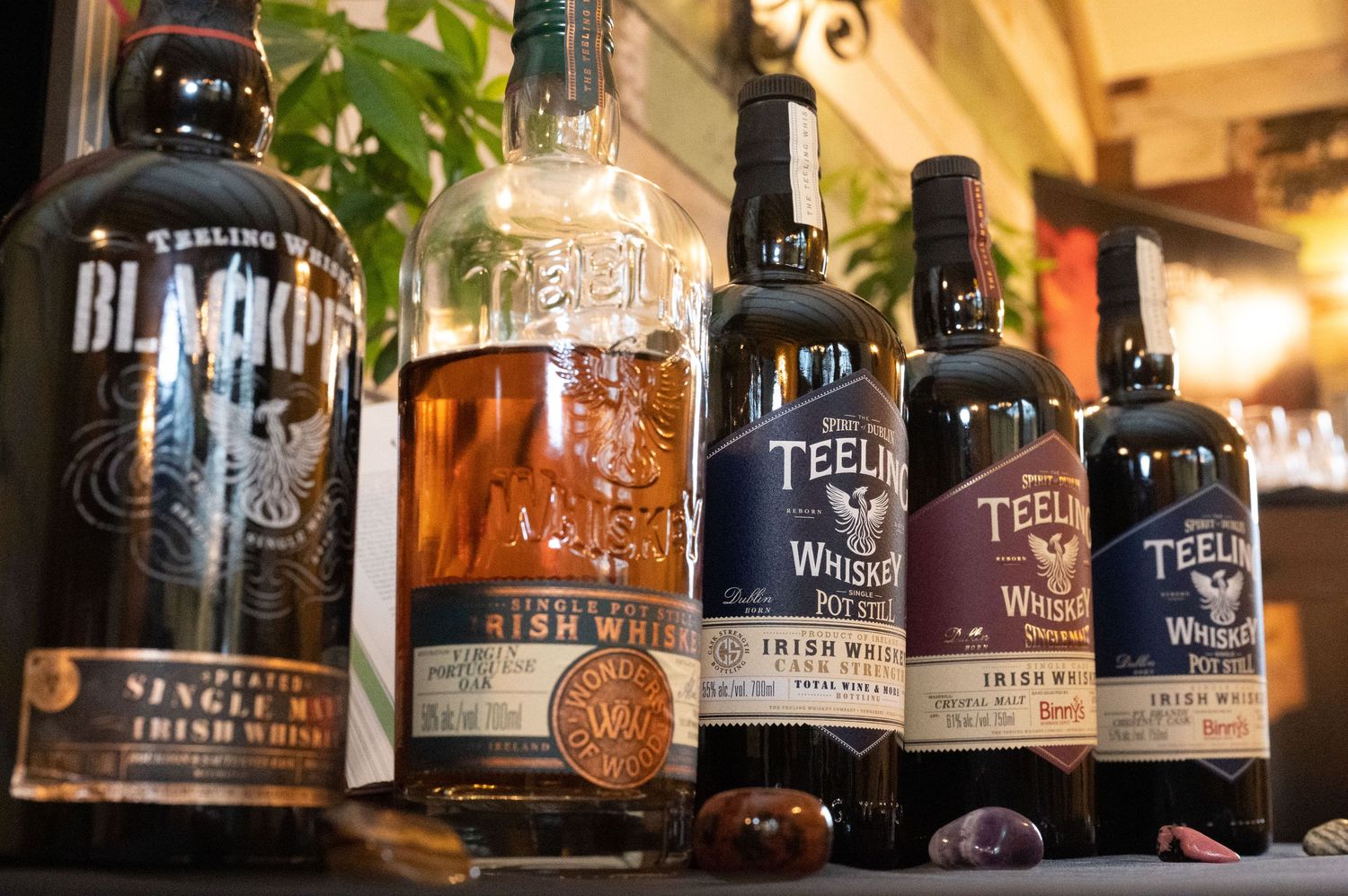Collection of premium whiskey and liquor bottles displayed on a dark wooden shelf with ambient lighting.