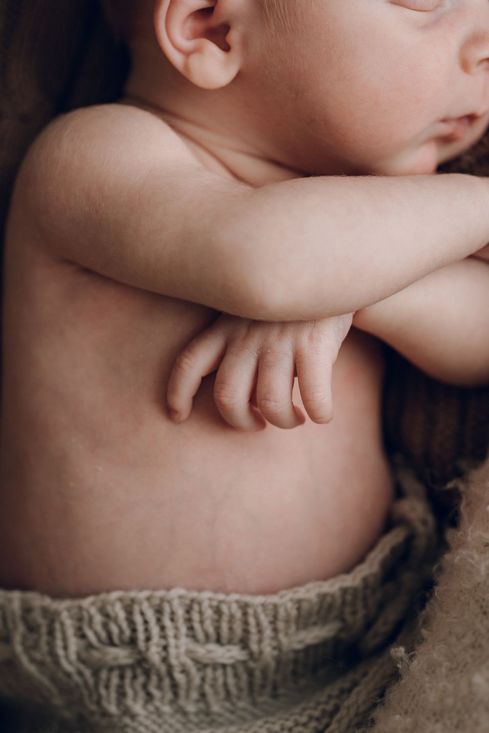 Close-up details of sleeping newborn wearing knit diaper.