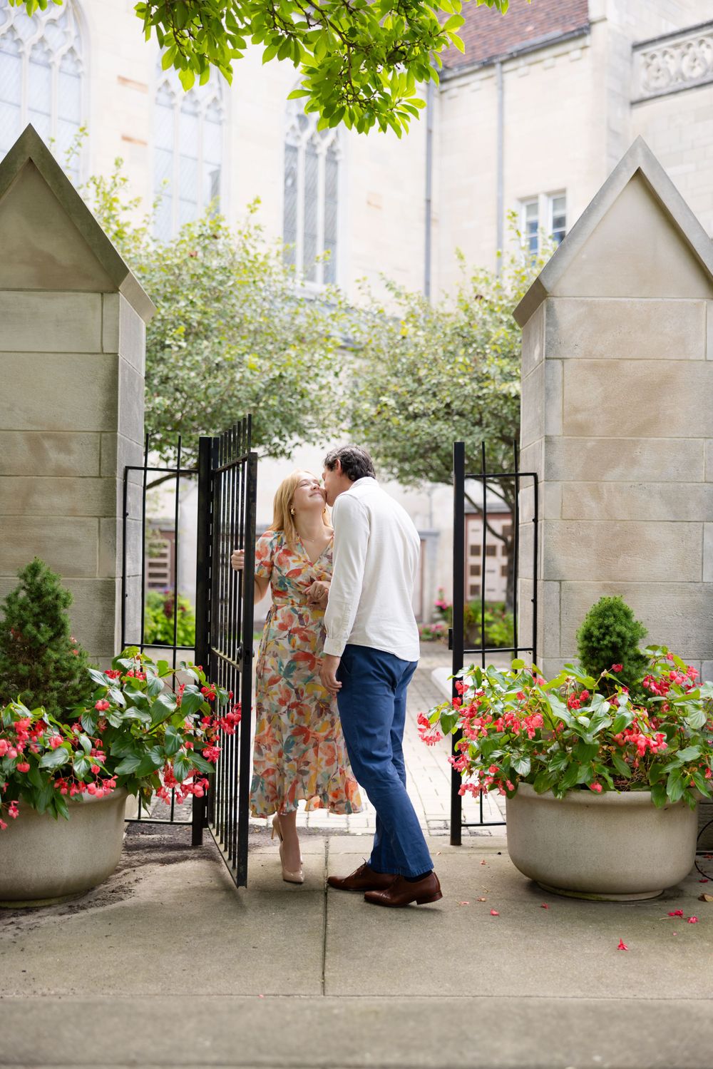A sweet moment shared between a couple at a garden gate with blooming flowers.
