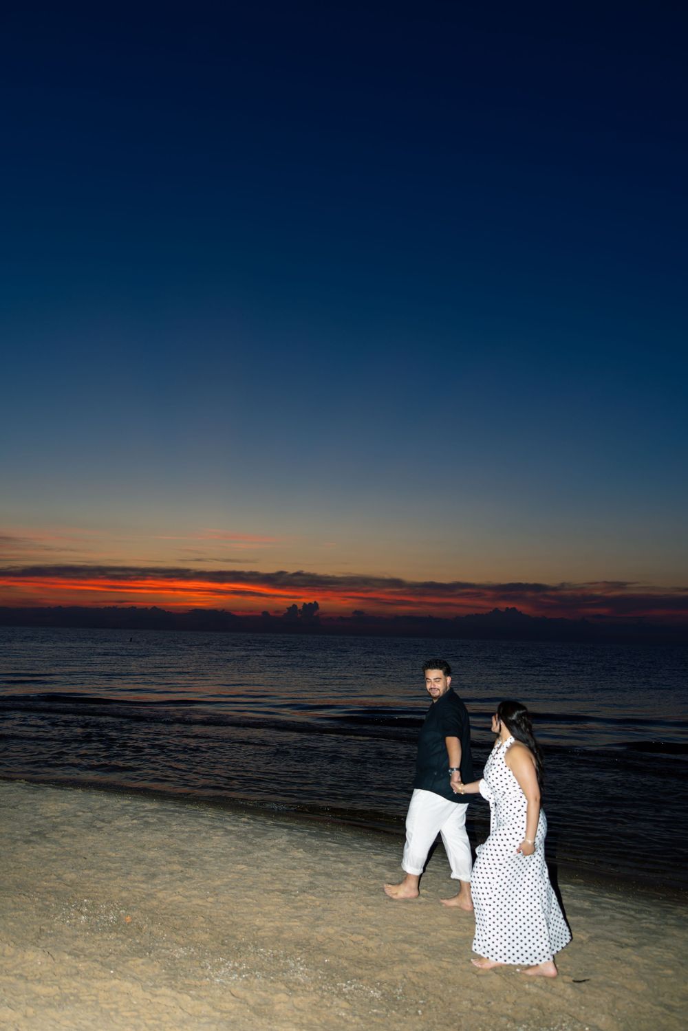 At Indiana Dunes, A couple sits together on the beach during sunset with the ocean stretching to the horizon.