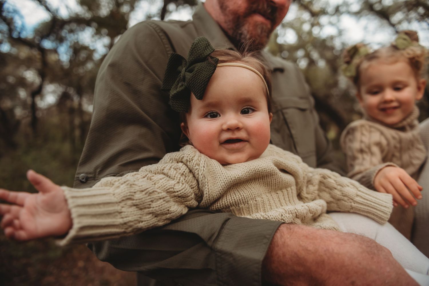A toddler wearing a cozy knit sweater enjoys family time outdoors during autumn.