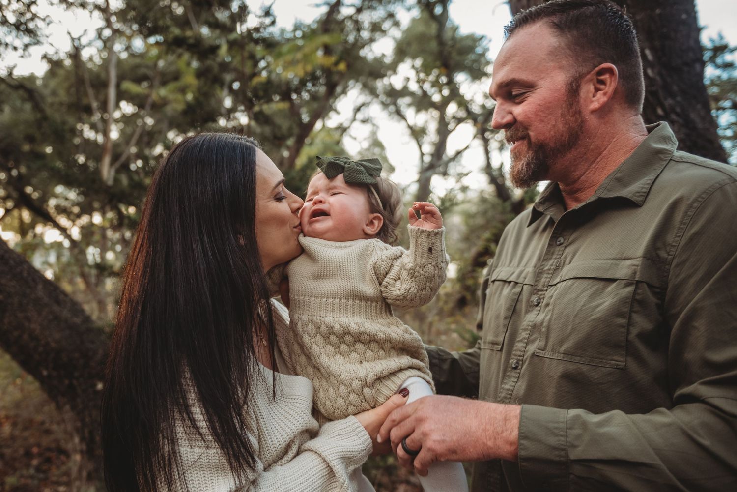 Family shares joyful moment together outdoors among trees on an autumn day.