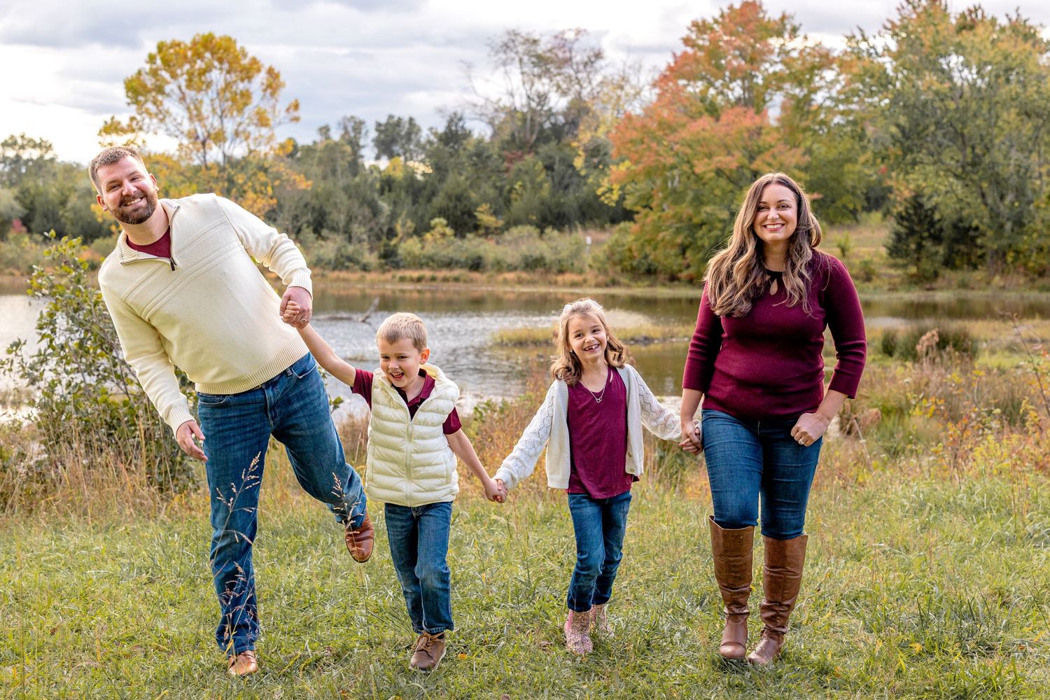 Happy family holding hands while walking through a scenic fall meadow.
