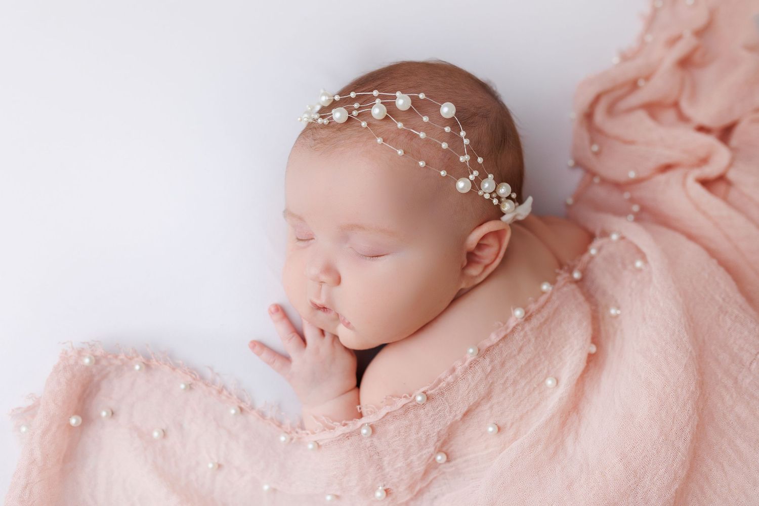 Delicate newborn photography collage featuring soft pink tones and white pearl accents against a light background.