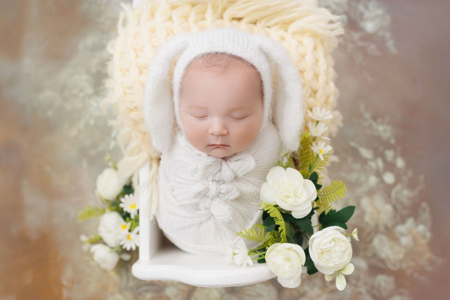 A sleeping baby in white attire surrounded by delicate white roses and soft dreamy lighting.