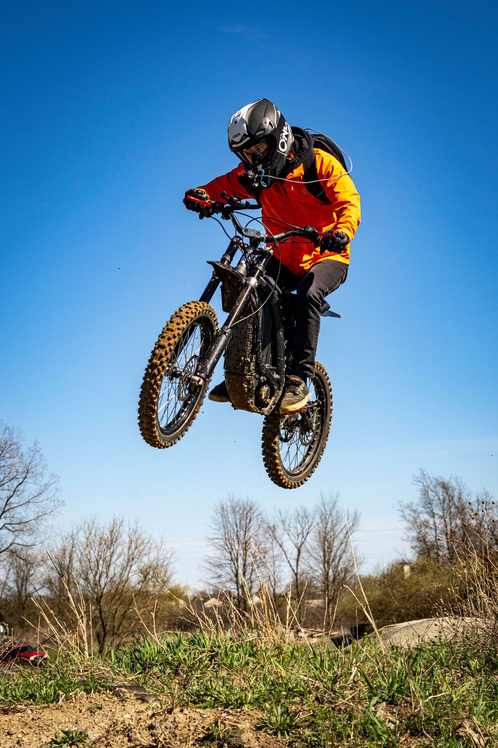 Motocross rider in orange and black gear soaring through the air on a dirt bike.