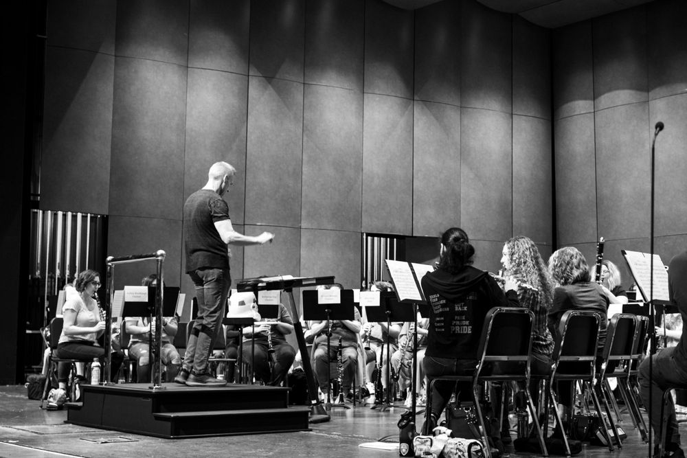 Black and white photo of orchestra conductor leading musicians during performance.