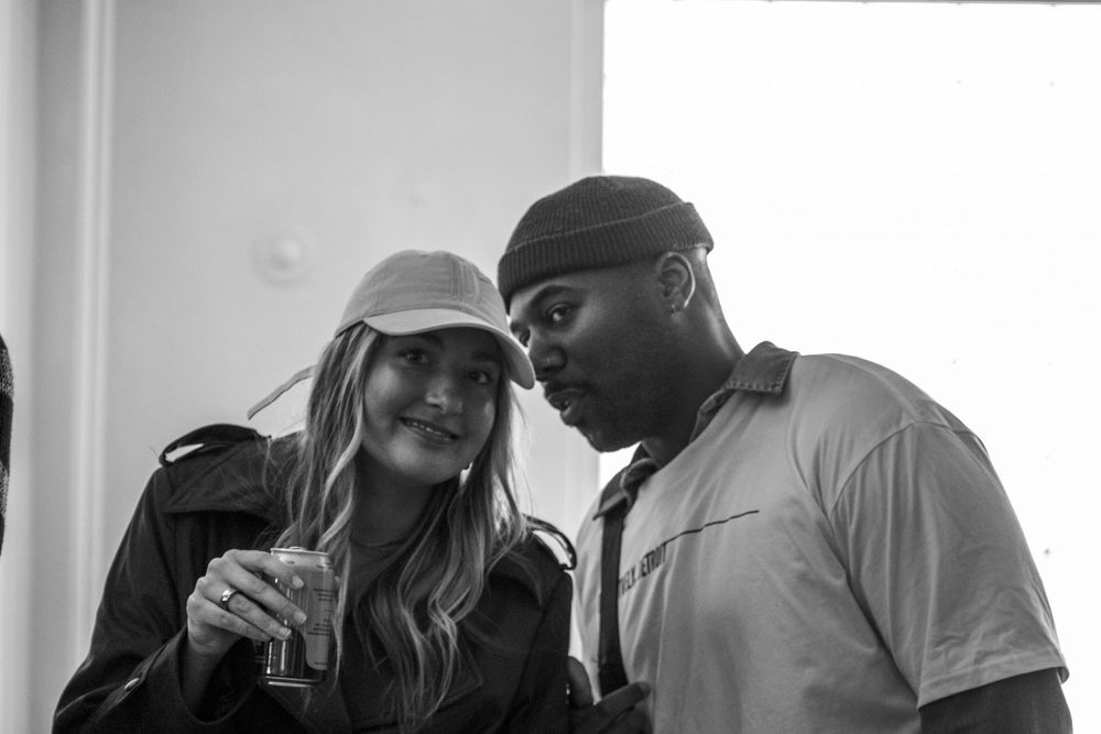 A man and woman sharing a candid moment at a social gathering, captured in black and white photography.