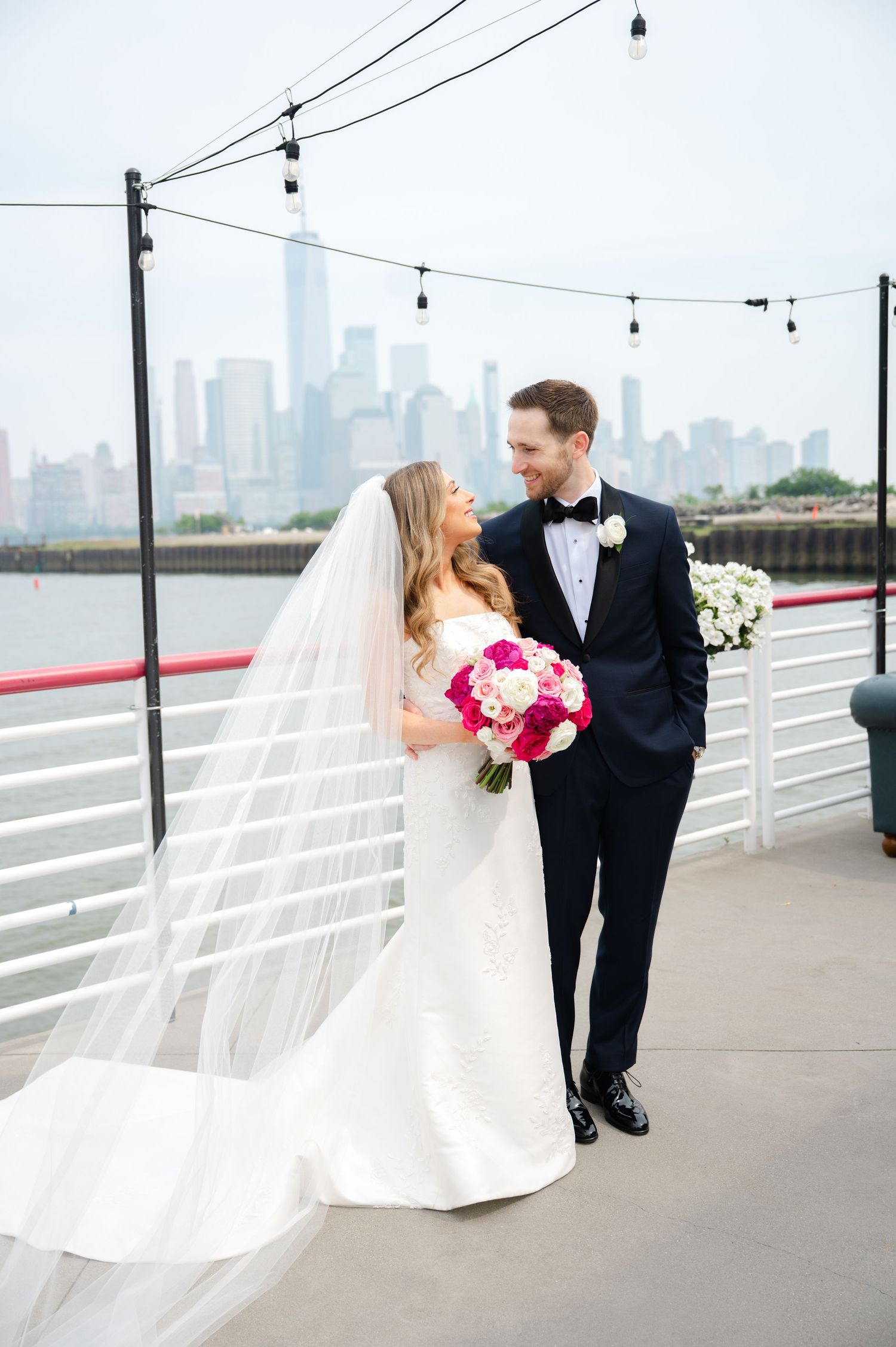 Romantic wedding portrait on stone steps with greenery backdrop.