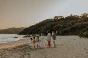 A group enjoys a tranquil evening on a secluded beach with hills in the background during golden hour.