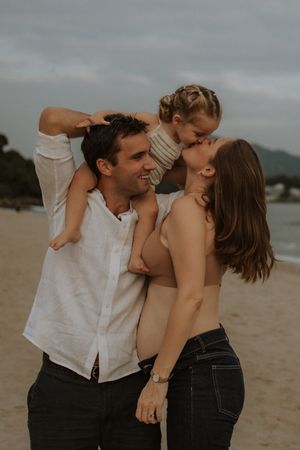 A couple shares intimate moments on a cloudy beach in a series of candid romantic photos.