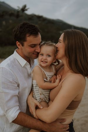 A family shares tender moments together during a sunset photoshoot at the beach.