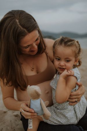 Sweet candid moments between parent and child playing together on a cloudy beach day.