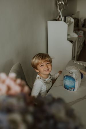 A series of five candid photos showing a young child reaching for items on a kitchen counter in natural light.