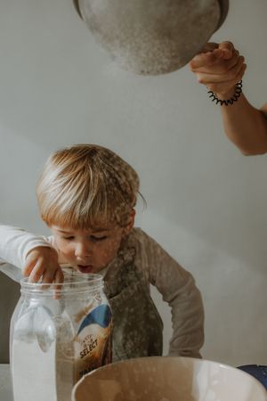 A child blows into a glass jar creating a magical cloud of flour or powder in a sequence of candid photos.