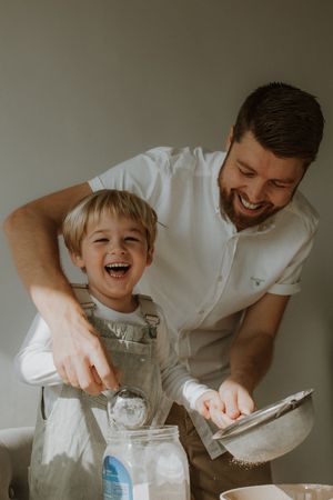 A joyful moment of baking together in the kitchen as they mix ingredients in a glass jar with white clothing.