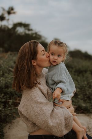 A tender moment captured outdoors as parent and child share a sweet embrace while wearing cozy knit sweaters.