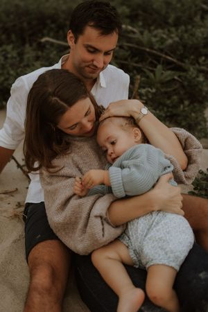 A family shares tender moments together while sitting outdoors in a natural setting during golden hour.