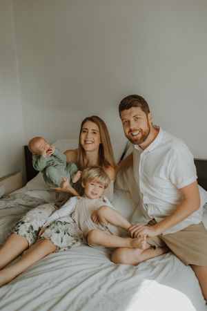 Family spending quality time together while relaxing on a cozy white bed.