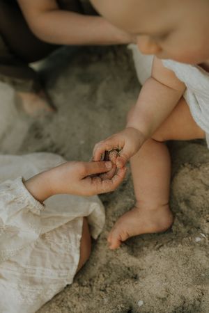 A series of photos showing tiny bare feet playing in sand, with a white dress hem visible in each frame.