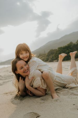 Candid beach photos showing playful moments while laying in the sand with mountains visible in the distance.