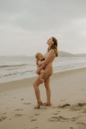 A tender moment between parent and child embracing on a misty beach during sunset.