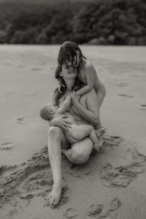 Artistic monochrome capture of tender moment between mother and infant resting on beach sand.