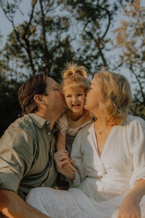 A sweet family moment captured in a series of candid photos showing kisses and laughter in warm sunlight.