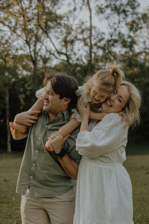 A couple shares joyful laughter and embraces while enjoying a casual outdoor photoshoot in a natural setting.