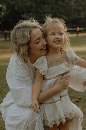 A heartwarming sequence of candid moments between a parent and child in white lace dresses playing outdoors.
