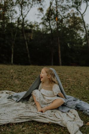 A candid lifestyle photo of someone laying on a blanket outdoors in a natural wooded setting.