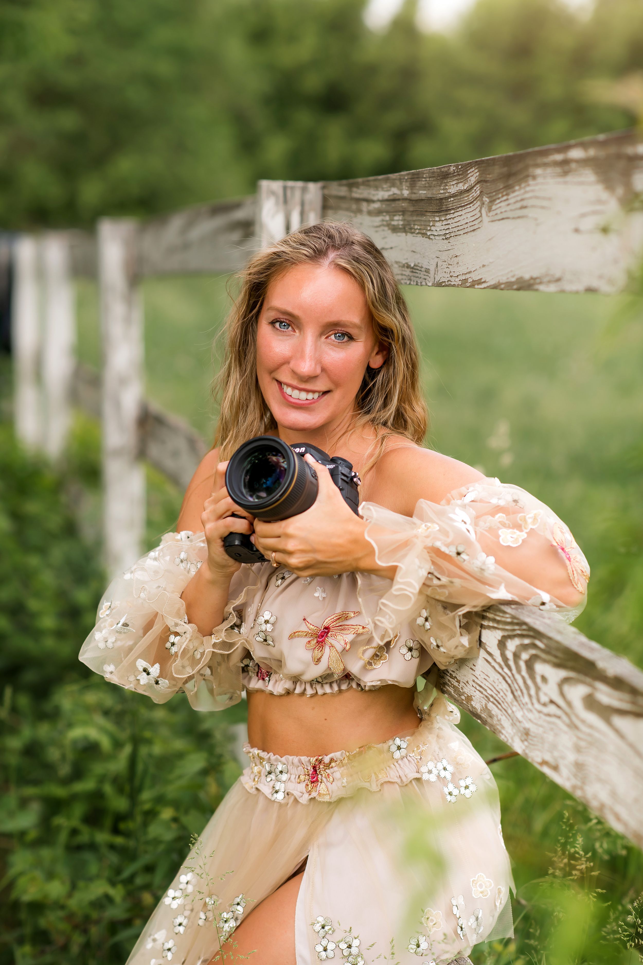Professional photographer in black dress poses with camera against gray studio backdrop in creative sequence.