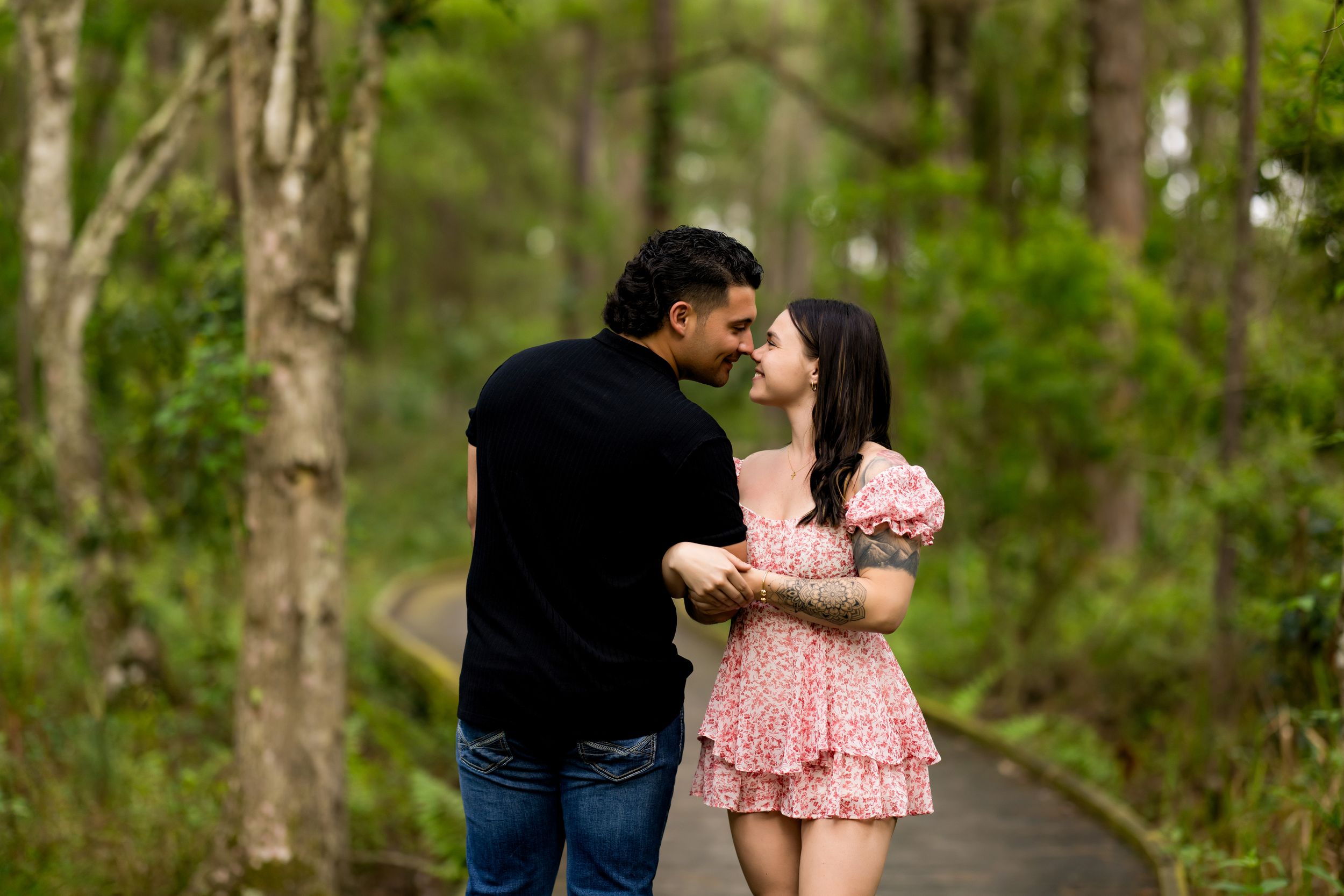 Romantic couple embracing on wooden path through green forest.
