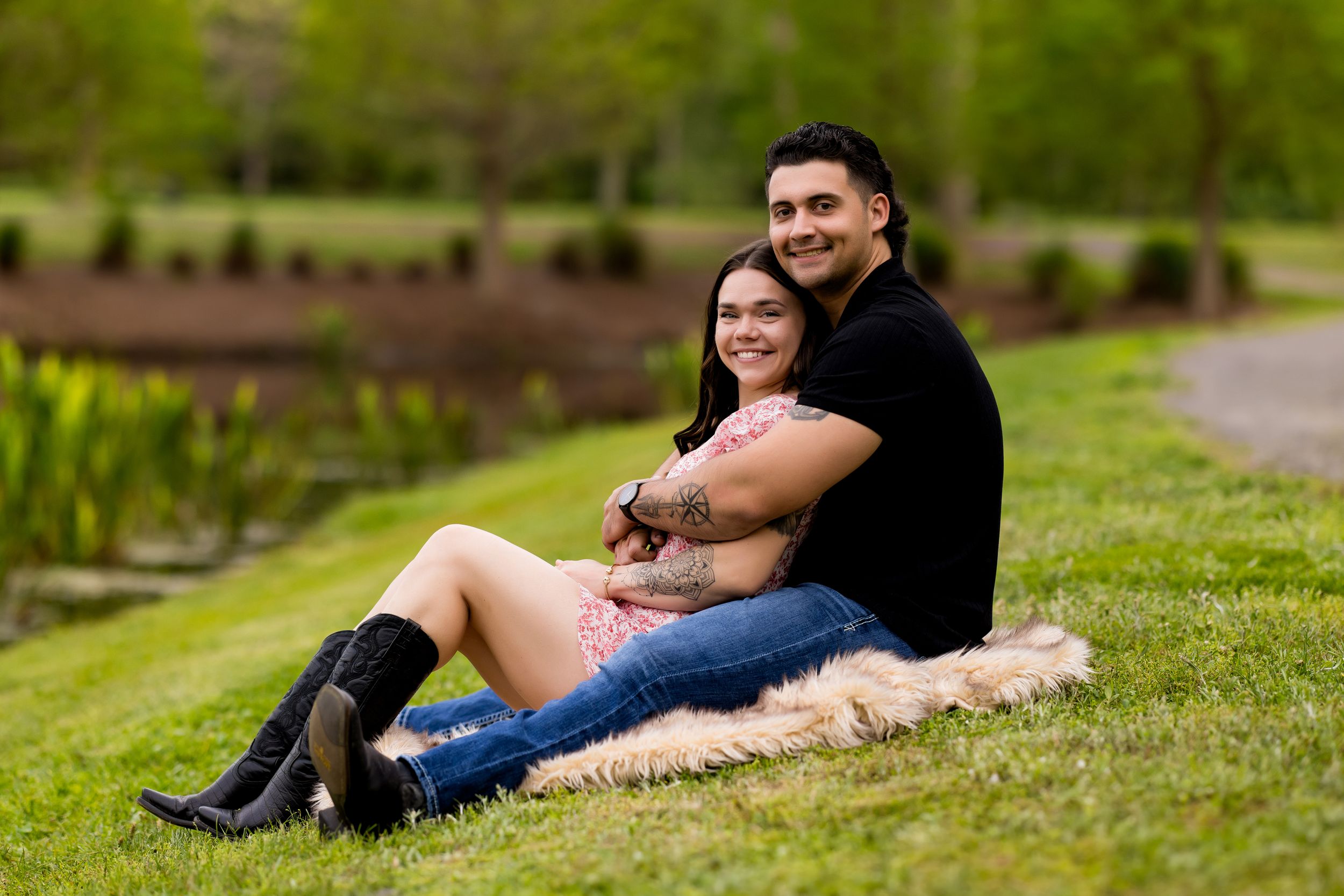 Couple relaxing on blanket in grassy park setting.