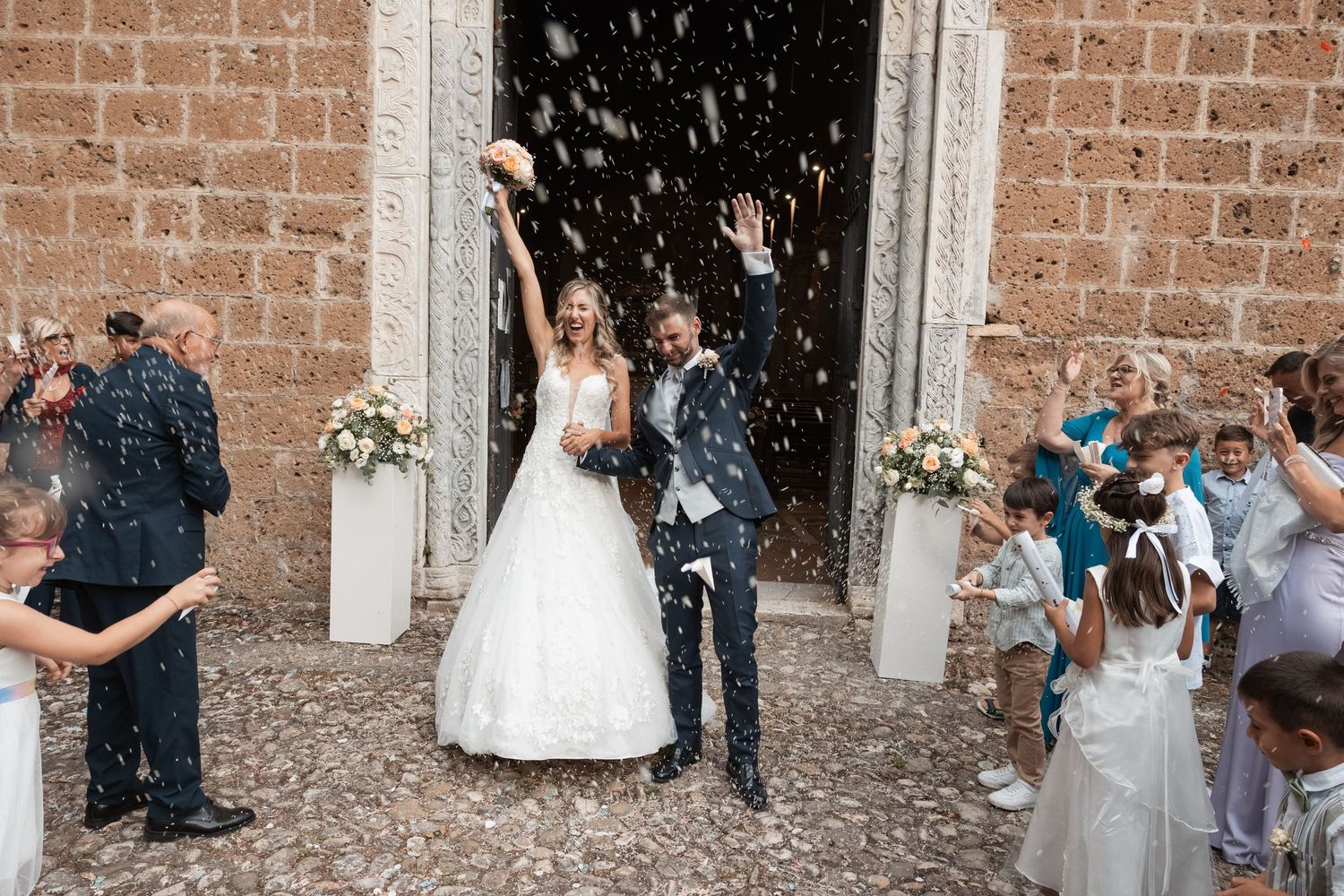 Wedding celebration outside a historic church with ornate turquoise doors.